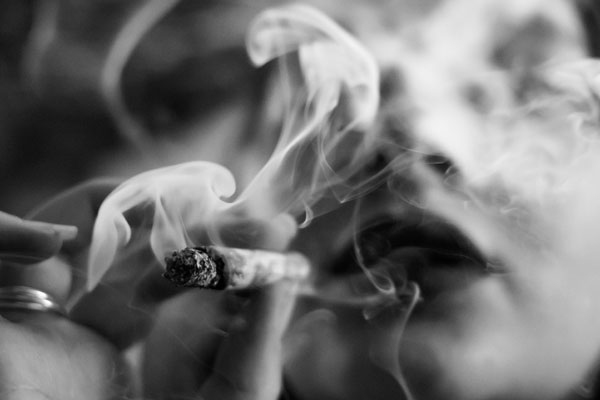 Closed-up of woman holding a cigarette with a thick smoke, which is the header image of "cannabis smoking and growing to be legal" blog.