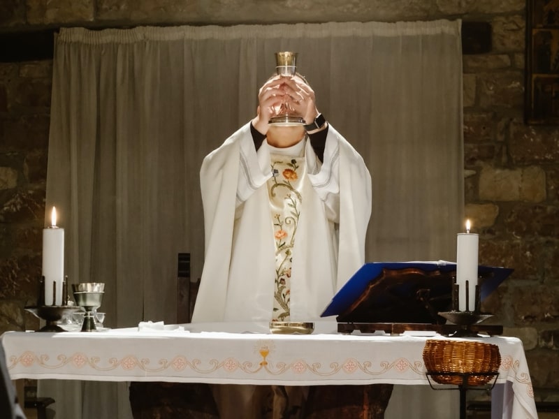 A cardinal raising a cup and standing in front of a table with candles, mantle and represents the "cardinal convictions quashed by the high court".