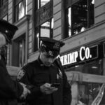 2 police officer standing and looking on their phones representing the page about "distributing an intimate image".